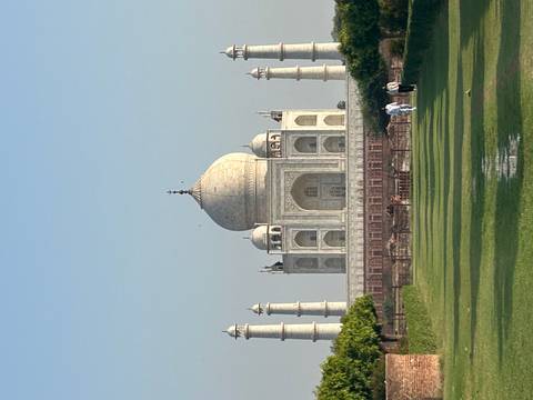 Clear daytime view of the Taj Mahal across manicured lawns from the Mehtab Bagh side.