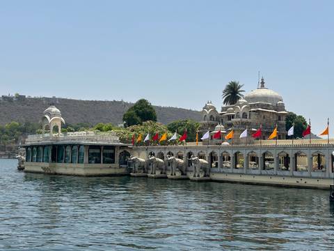 Lakeside palace complex with elephant statues and colorful flags on Lake Pichola.