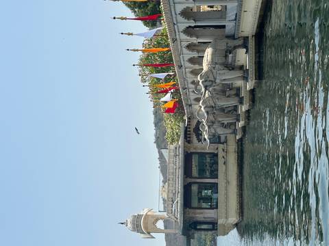 Row of carved elephant statues along the lake edge with colorful flags fluttering nearby.