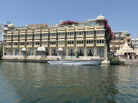 Lakefront heritage hotel building with flowering balconies and a boat moored on the water.