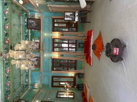 Ornate royal interior hall with teal walls, chandeliers and traditional floor seating.