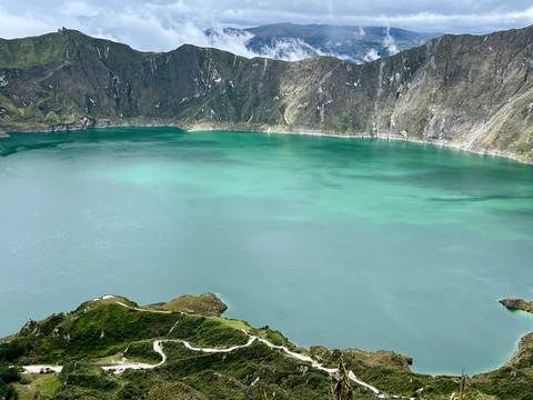 Turquoise crater lake surrounded by sheer volcanic walls and green ridges.