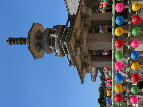 Stone pagoda decorated with colorful lanterns against a bright blue sky