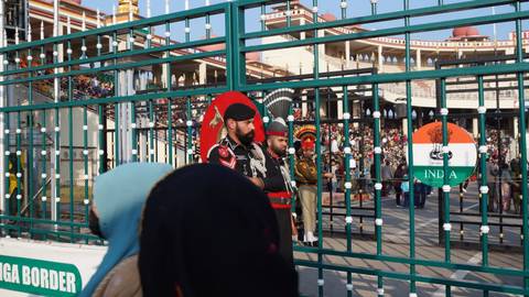 Pakistani and Indian soldiers stand at iron gates during the border ceremony as spectators look on.