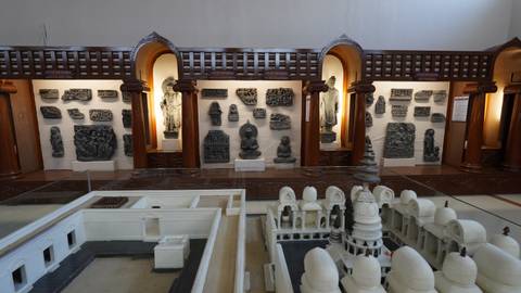 Museum gallery displaying Gandhara stone reliefs with a scale model of ancient architecture in the foreground.