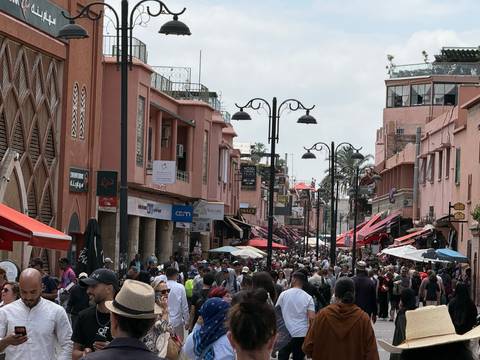 Bustling pedestrian street packed with shoppers and colorful storefronts in a Moroccan city.