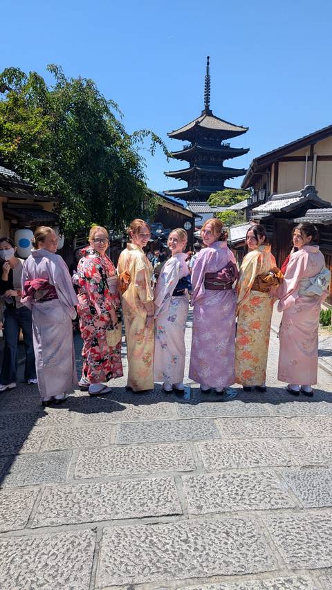 Friends wearing kimonos smiling for photo on a historic Japanese lane