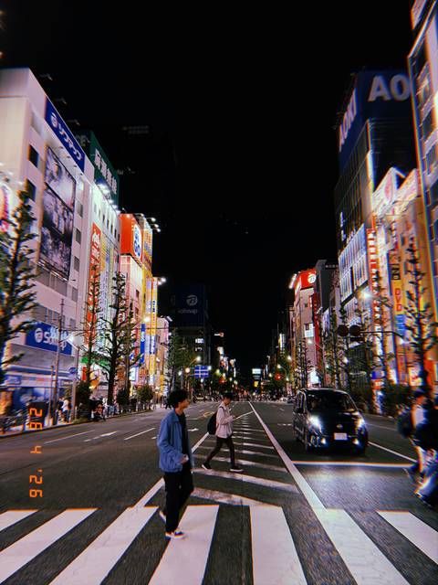 Vibrant Tokyo street at night filled with neon signage and people crossing