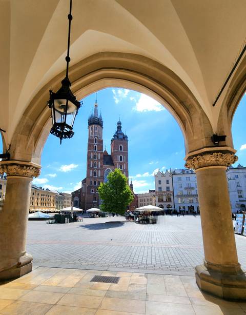 St. Mary’s Basilica framed by an archway on Krakow’s main square under a blue sky.