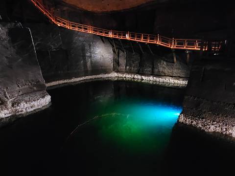 Underground saline lake illuminated with blue light inside a salt mine chamber.