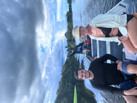 Small group in a motorized canoe on an Amazon river with dramatic clouds overhead