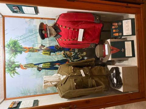 Display case with historical Nepali military uniforms, medals and photographs in a museum