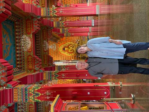 Couple standing inside a richly decorated Buddhist hall with golden Buddha statue