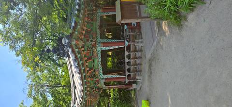 Colourful painted Korean pavilion set in a leafy park on a sunny day
