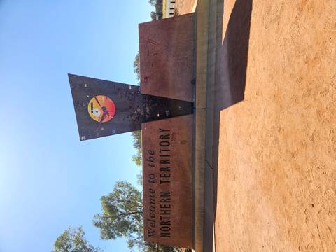 Welcome sign marking the border of the Northern Territory under a clear blue sky.