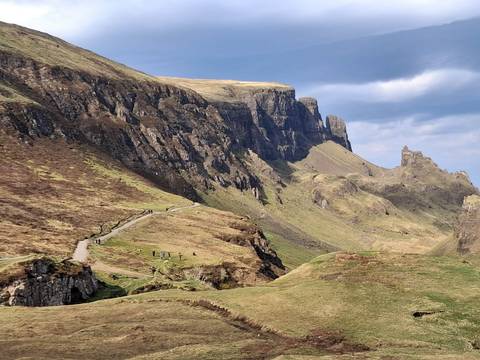 Dramatic cliffs and winding path of the Quiraing on the Isle of Skye with tiny hikers below