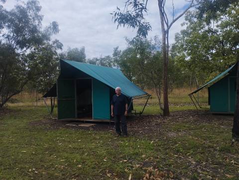 Camper standing in front of a canvas safari tent at a bush campsite