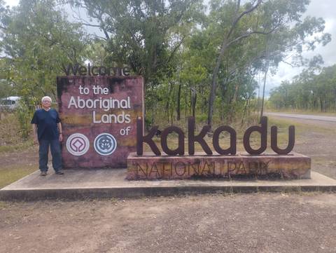 Traveler beside the welcome sign to Kakadu National Park on a rural roadside