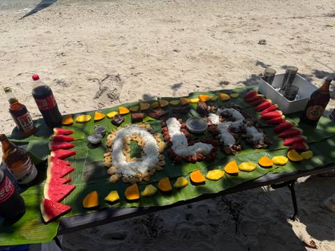 Beachside boodle-fight spread of rice, meats and fruit laid on banana leaves