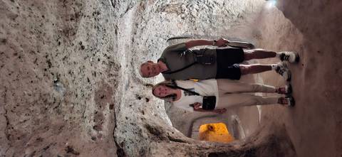 Older couple posing inside a dimly lit volcanic rock chamber of Cappadocia underground city