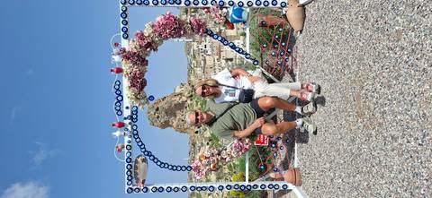 Smiling couple seated in heart-shaped photo frame overlooking Cappadocia town and rock butte