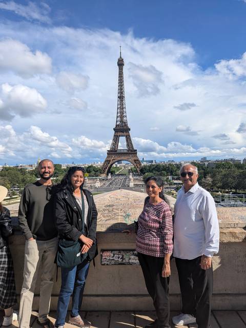 Travellers pose before the Eiffel Tower against a backdrop of dramatic clouds.