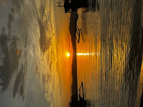 Golden sunset over calm sea with silhouette of traditional outrigger boats.