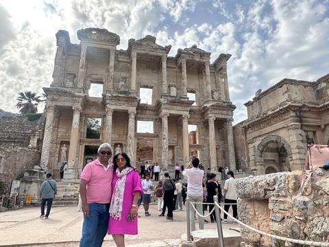 Couple posing in front of ancient marble Library of Celsus with tourists milling around