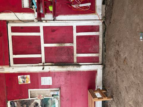 A weather-worn red wooden door with peeling paint and dirt marks