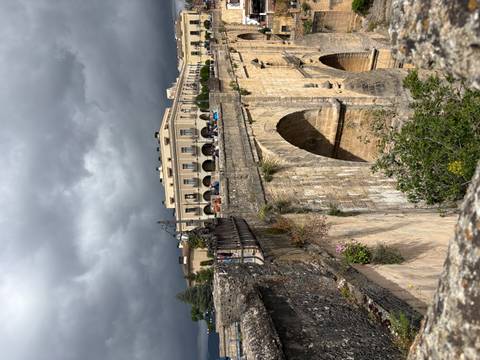 Dramatic arched bridge spans a deep gorge below stormy skies with historic Ronda buildings lining the edge.
