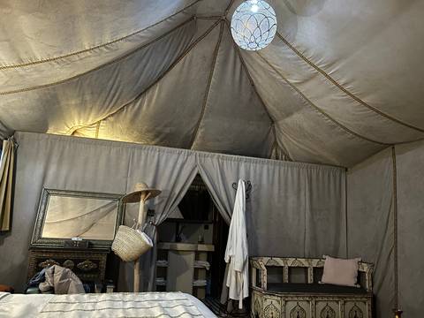 Cozy interior of a canvas desert tent with traditional furnishings and soft lighting.