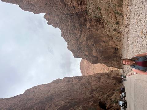 Visitor stands beneath towering sandstone walls of a narrow rocky gorge.