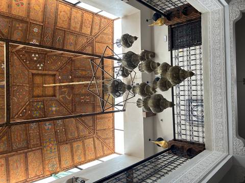 Ornate Moroccan chandelier cluster hanging beneath an elaborately painted wooden ceiling.
