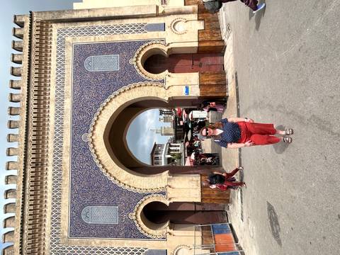Traveler stands before the ornate blue-tiled Bab Bou Jeloud gate in Fes medina.