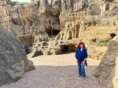 Visitor stands among weathered limestone caves and rock formations on a cobblestone path.