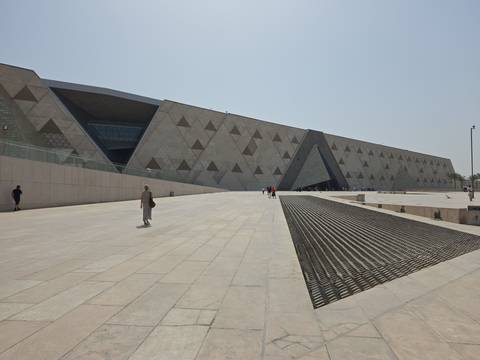 Modern angular façade of the Grand Egyptian Museum with a vast stone plaza in front