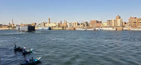 Boats glide along the wide Nile River with Cairo’s skyline of minarets and buildings lining the opposite bank.