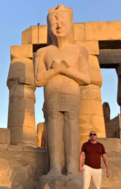 Close-up of a colossal sandstone pharaoh statue bathed in warm evening light at Luxor Temple.