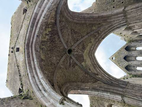 Gothic stone archway interior of a ruined cathedral looking up to the sky.