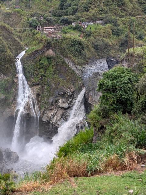Twin powerful waterfalls plunge through lush green Ecuadorian jungle, mist filling the air.