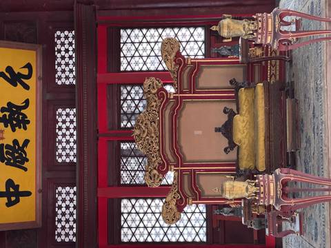 Ornate imperial throne room with red lacquer panels, golden dragons and a yellow silk seat inside the Forbidden City.