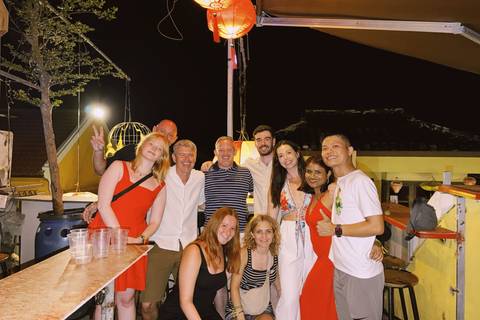 Lively group of travellers posing together at a rooftop bar during a night out.