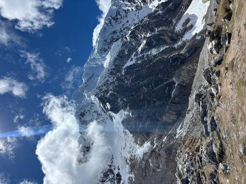 Sunbeam streaks across towering rocky Andes with patches of snow under a deep blue sky