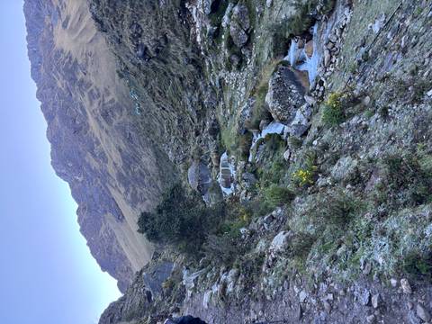 Rocky stream cascades through a rugged alpine valley beneath golden grassy slopes