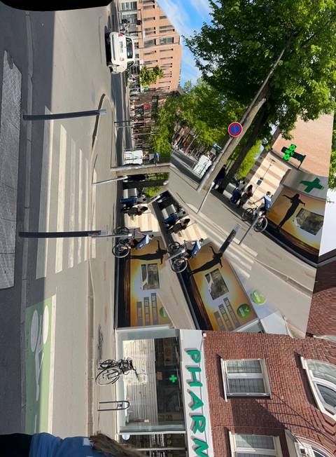 A distorted multi-exposure city street scene with cyclists and storefronts appears mirrored and chaotic.