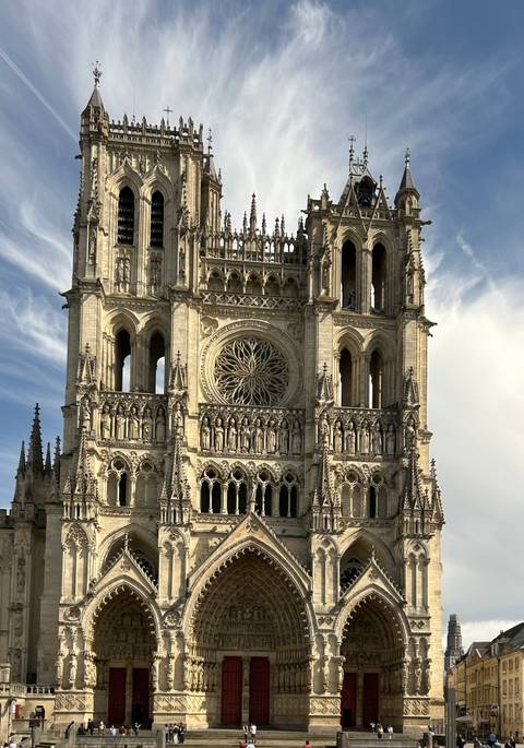 A detailed Gothic cathedral façade rises dramatically against a streaked blue sky.