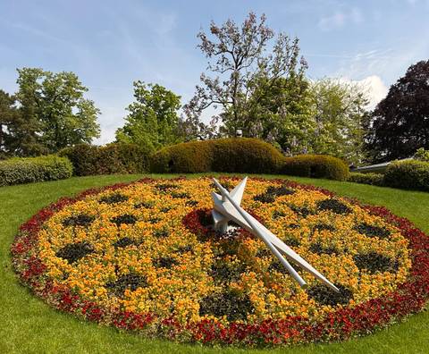 A famous floral clock made of bright orange and yellow blooms forms a giant timepiece in a park.