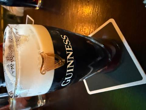 A freshly poured pint of dark Guinness stout sits on a coaster at a pub table.