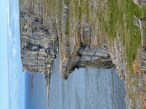 Steep, rugged sea cliffs drop dramatically into deep blue waters along an Atlantic coastline.