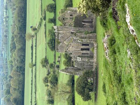 Ancient stone ruins sit amid patchwork green farmland stretching into the distance.